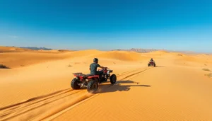 Tourists riding quad bikes across the golden sand dunes of Tunisia's Sahara Desert at sunset, with a guide leading the way