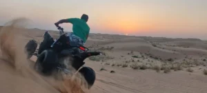 Tourists riding quad bikes across golden Dubai desert dunes, kicking up sand as they navigate the challenging terrain